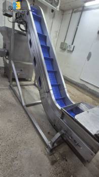 Inova Industrial inclined stainless steel conveyor belt with cleats.